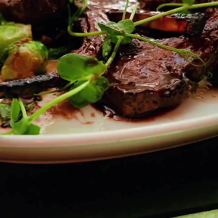 Sliced grilled steak with roasted vegetables and microgreens